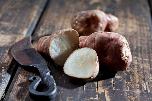 Whole and sliced Jerusalem artichoke and an old knife on wood