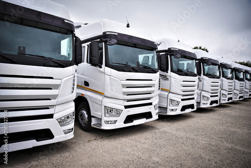Many trucks and tractor-trailers parked in a commercial vehicle yard. Heavy transport equipment for freight logistics, cargo transportation, and road haulage.