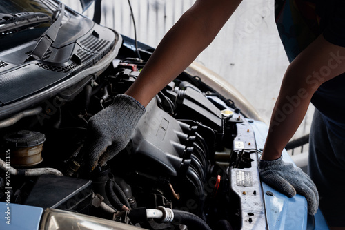 Foto Professional auto mechanic hand in glove inspecting wire harness and engine parts under car hood