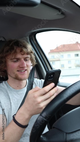 Vertical screen motorist smiles at content on a smartphone and takes attention away from the road while the moving vehicle creates an extremely dangerous safety situation
