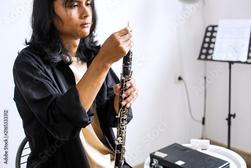 Obraz na płótnie Young Asian Musician Carefully Inserting Reed Into His Oboe During Practice at H