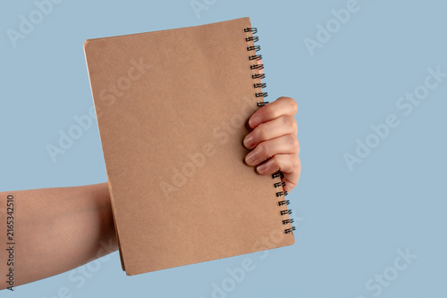 Brown notebook in hand on blue background