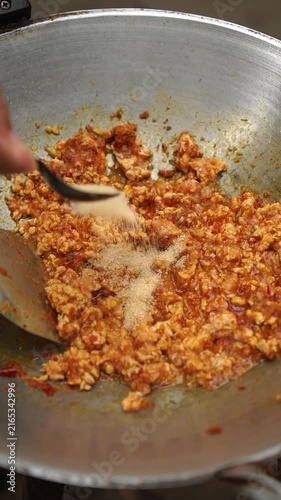 Cooking Thai stir-fried chicken with pickled bamboo shoots (Gai Sub Phad Nor Mai Dong) by sautéing curry paste, chicken, and sweet basil.