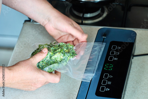 Vacuum sealer removes air from bag with broccoli during vacuum packaging, helping preserve fresh vegetables for longer storage.