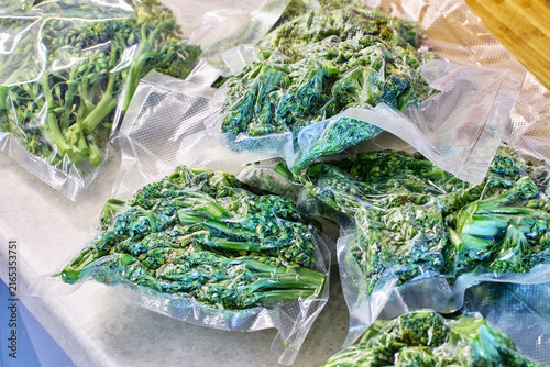 Vacuum packaging, freezing, broccoli portions rest on kitchen countertop, showing practical food storage after home meal preparation.