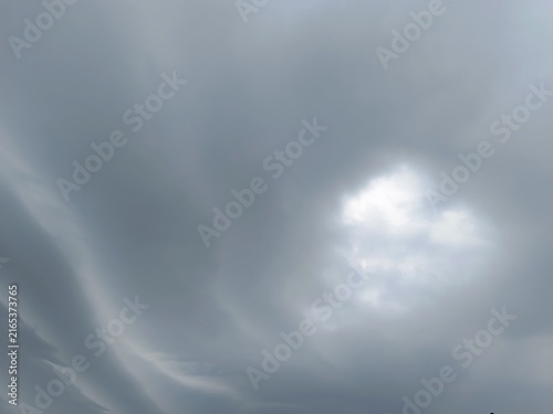 Thick grey clouds in an overcast sky. Dramatic weather background with hidden sun. Approaching storm atmosphere