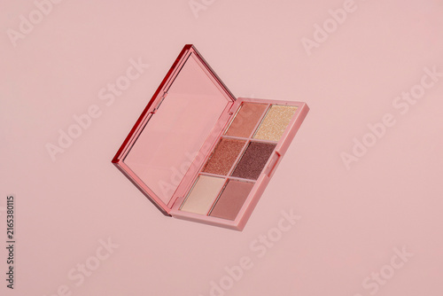 Eyeshadows palette in brown and purple shades on pink background