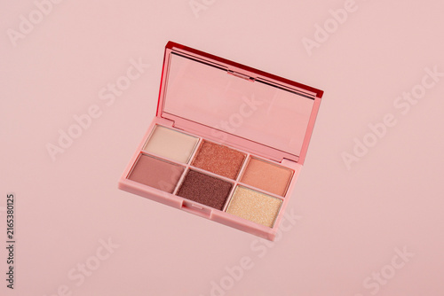 Eyeshadows palette in brown and purple shades on pink background