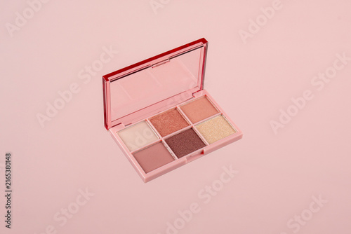 Eyeshadows palette in brown and purple shades on pink background