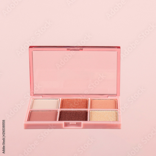 Eyeshadows palette in brown and purple shades on pink background