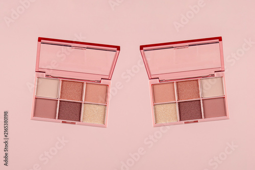Eyeshadows palette in brown and purple shades on pink background