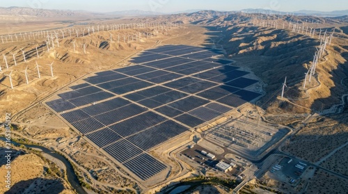 Aerial view of a large solar farm and wind turbines in a desert landscape for green energy.