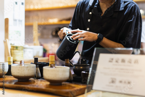 Obraz na płótnie Barista pouring hot water from a black gooseneck kettle into a traditional teapot