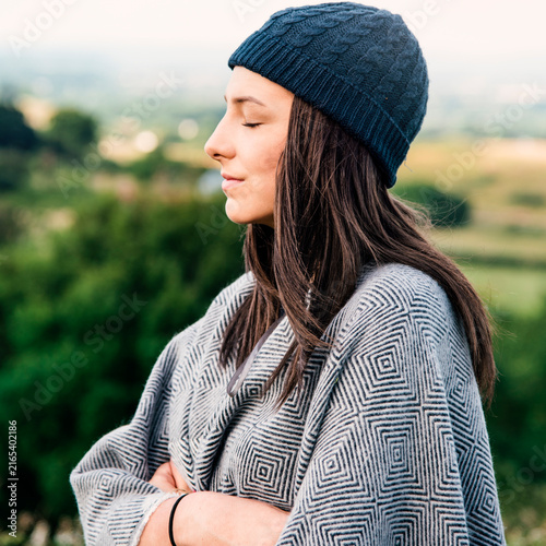Foto Woman in a beanie and patterned shawl enjoying nature outdoors.