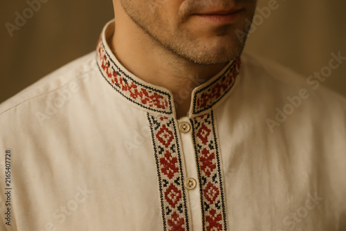 Close up of man wearing embroidered traditional shirt with geometric collar detail