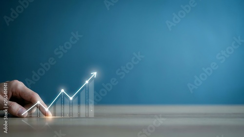 A person using their hand to touch a digital growing graph icon representing financial success business growth and economic performance