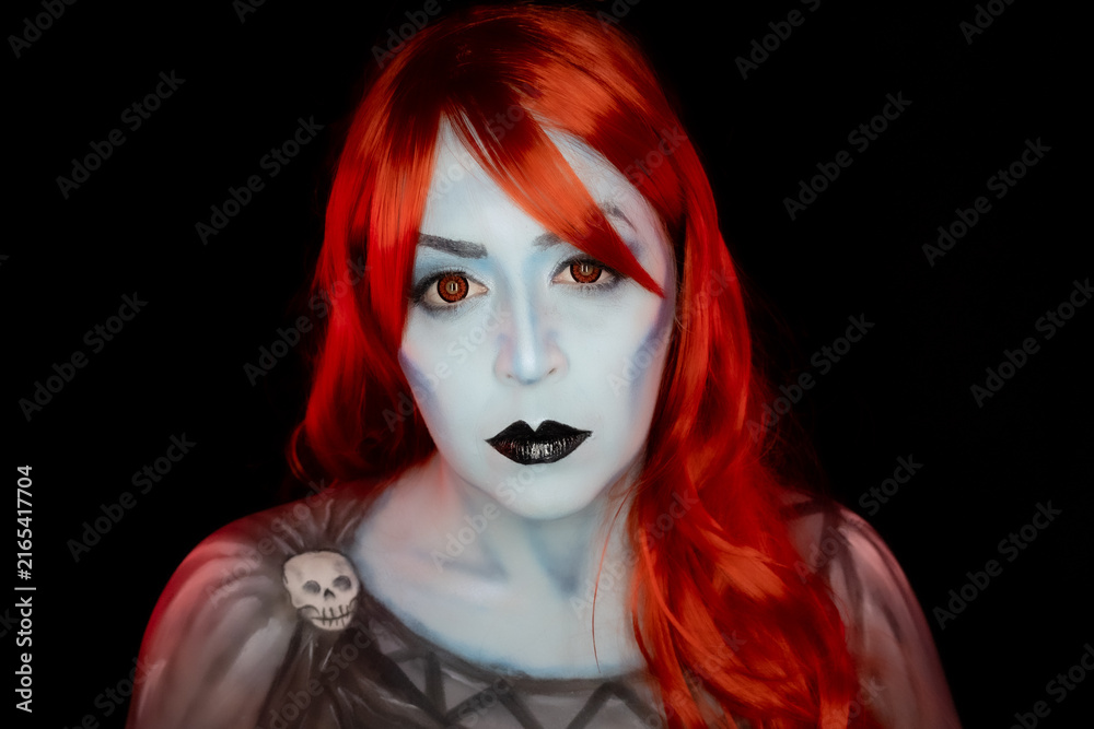 Obraz premium Fantasy portrait of a woman with vivid colored hair, blue-toned skin, red eyes and dramatic dark makeup, creating a striking supernatural character on a dark background.