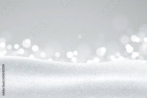 Sparkling snowdrift with glowing bokeh lights in the background. Winter holiday backdrop with glitter texture 