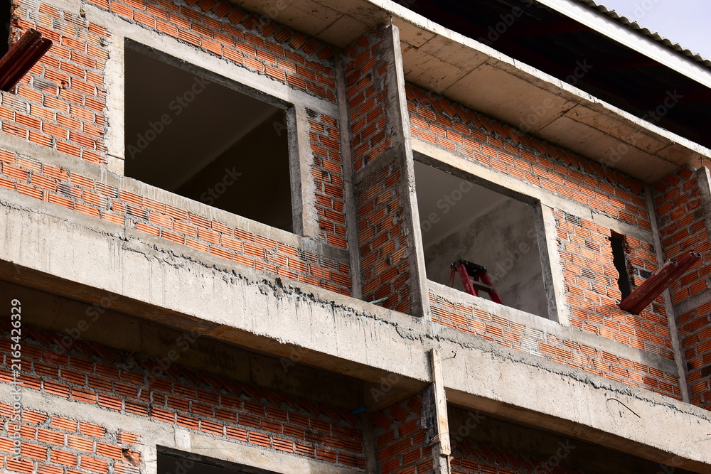 Naklejka premium exterior view of brick house under construction with concrete structure