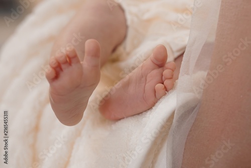 Close up of newborn baby feet resting on soft white fluffy blanket in bright high key lighting.