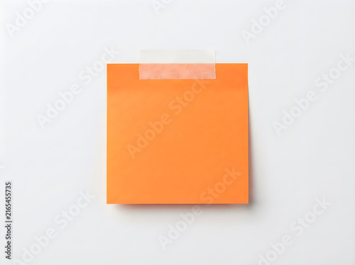 A square orange paper note attached with a strip of adhesive tape, isolated on white background