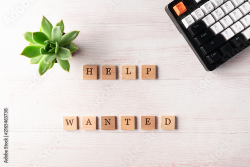 Office desktop with keyboard, succulent flower and text Help Wanted on the wooden cubes. Hiring and recruitment of staff concept. 