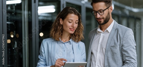 In a modern data center, two IT experts examine network equipment, focusing on system performance and infrastructure enhancement.