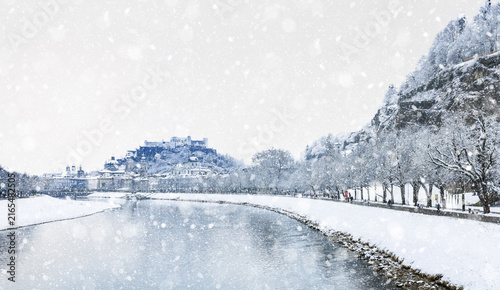 Salzburg at river Salzach - Dreamy cold white winter landscape with falling snow at Müllner Steg Bridge with view at Promenade and fortress Hohensalzburg - concept of travel - Austria Europe 2026