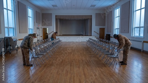 Volunteers arrange chairs in a community hall at dawn