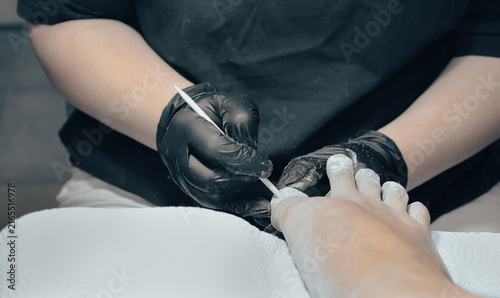 фотографія Close up of a professional nail technician using a wooden stick during a pedicure procedure