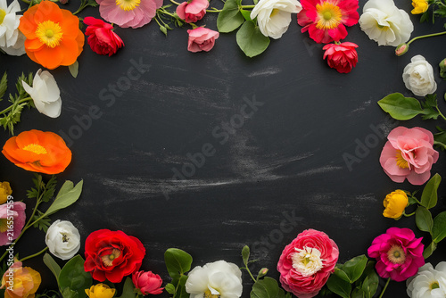 Vibrant flowers arranged around the edges of a dark textured surface.