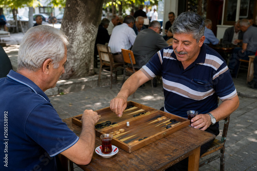Older Turkish Neighbors Playing Backgammon and Sharing Tea at a Shaded Outdoor Tea House during a Relaxed Afternoon Gathering