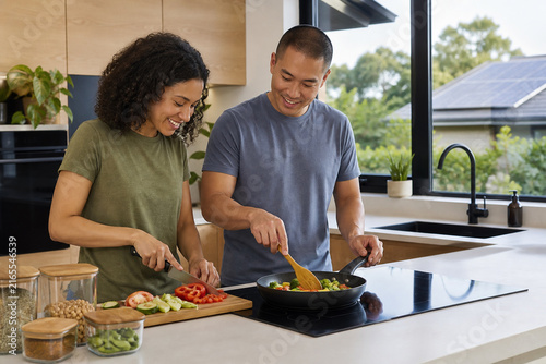 Diverse Couple Preparing a Healthy Vegetable Meal on an Energy Efficient Induction Cooktop in a Bright Solar Powered Modern Kitchen