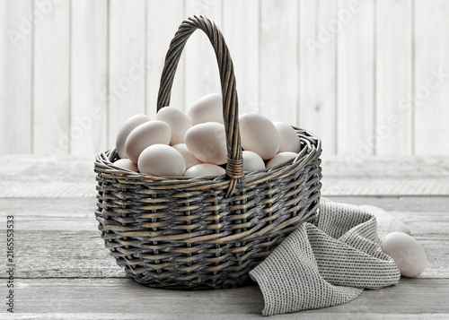 white eggs in rustic wicker basket on wooden table