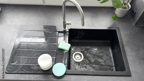 Kitchen sink with cleaning product and sponge being cleaned