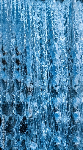 Blue waterfall cascade stream with dark rock background abstract water texture