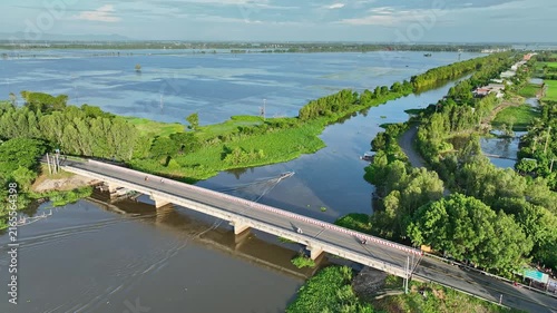 Drone view of a bridge and rural waterways surrounded by inundated fields and lush vegetation during the annual flood season in An Giang, Mekong Delta.