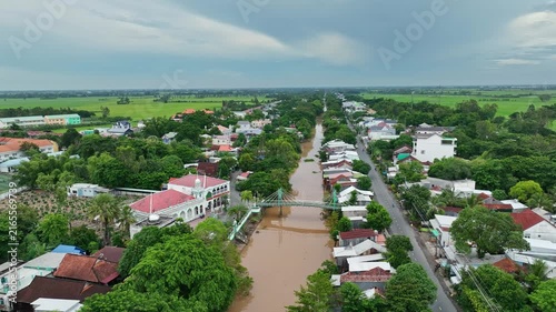 Drone view of floodwater surrounding a rural settlement, roads, homes, and green farmland in An Giang, Vietnam, during the annual Mekong Delta wet season.