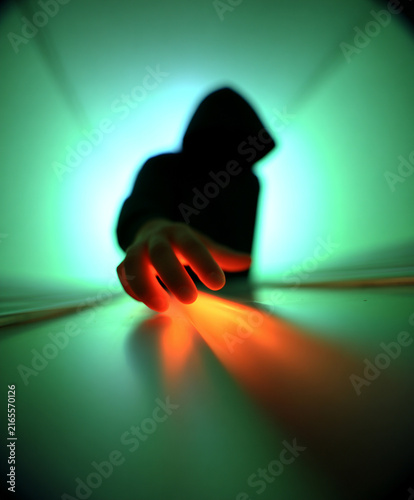 Hooded Person Reaching Forward with Glowing Orange Light on Hand