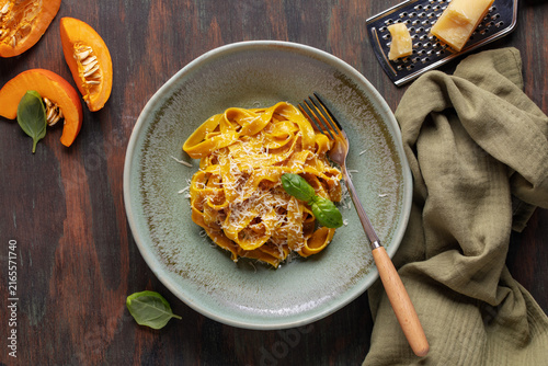Homemade pumpkin tagliatelle pasta with parmesan cheese in a plate on the table. Italian cuisine. Top view