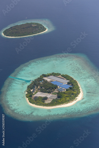 Aerial view of a tropical island with lush vegetation and white sandy beaches surrounded by turquoise coral reefs in the deep blue ocean in Baa Atoll, Baa Atoll, Maldives.
