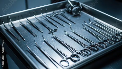 Surgical instruments neatly arranged on a metallic tray in a clinical setting.
