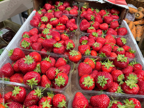 Ripe red strawberries in plastic trays on market display