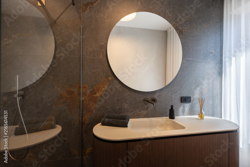 Canvastavla Bathroom vanity photographed with frameless shower glass and handheld fixture occupying the left side, beneath subdued indirect ceiling illumination