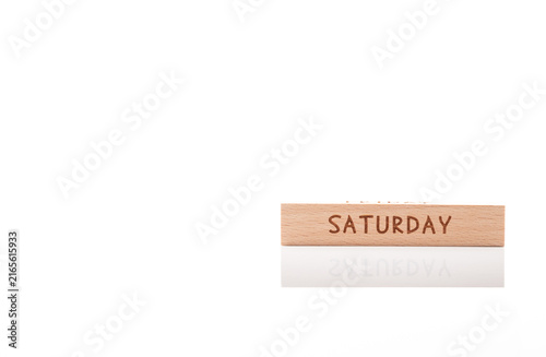 Photography Wooden cube with engraved word SATURDAY on white background with soft reflection