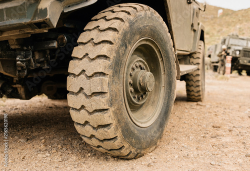 Close up of large heavy duty truck tire covered in dust while driving on unpaved dirt country road