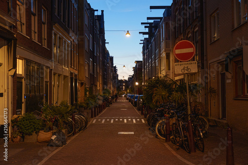 Canvastavla Quiet Amsterdam street lined with brick buildings, bicycles, and warm evening li