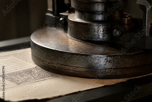 Close-up of antique printing press platen pressing textured paper, industrial.