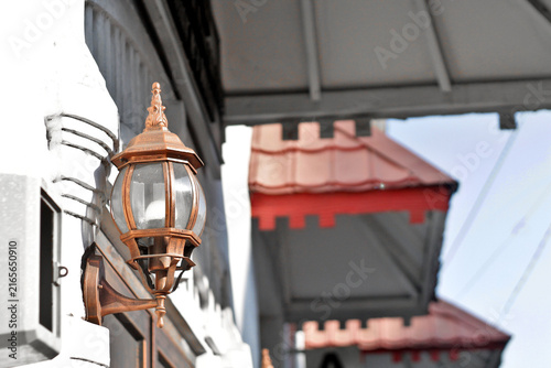 Vintage Wall Lantern On Historic Building Facade With Red Awnings And Ornate Copper Exterior Light