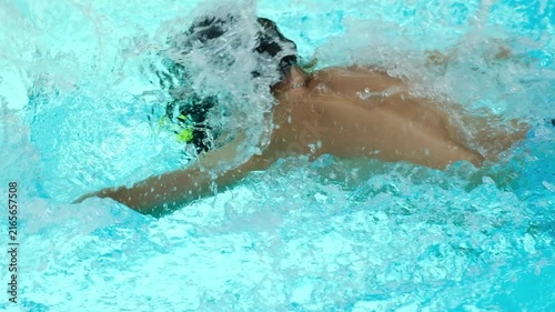 young boy swimming underwater in pool, practicing freestyle stroke with goggles and splashing water